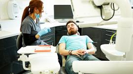 a dentist talking to a patient who is lying back in a dental chair