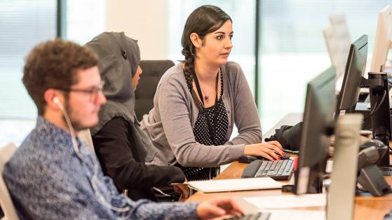 Three people working at computers in an office